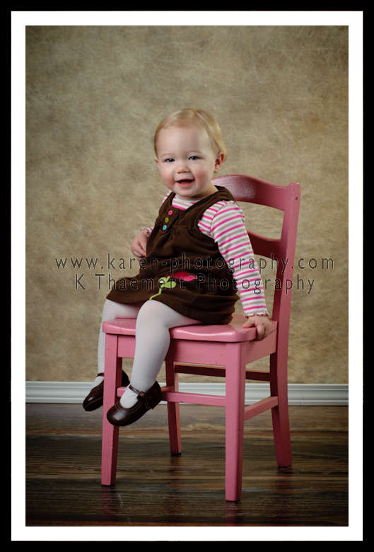 Photo of 1 year old girl on pink chair St Charles Baby Photography